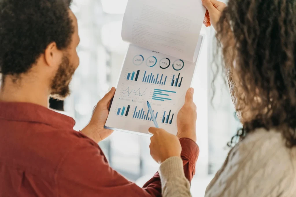 Dois profissionais analisando gráficos e métricas de desempenho em relatório de treinamento e desenvolvimento.