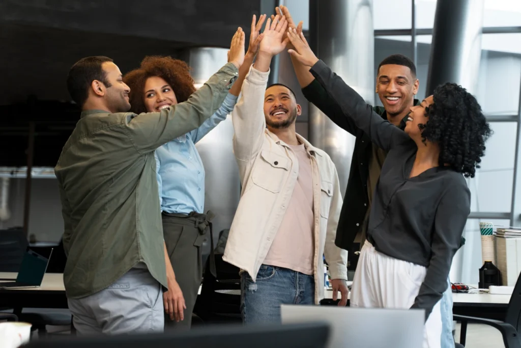 Equipe de funcionários celebrando com um toque coletivo de mãos, simbolizando sucesso no treinamento corporativo.