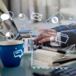 Profissional digitando em laptop com ícones digitais de comunicação, finanças e gráficos, representando plataformas LMS modernas.