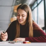 Mulher sorridente estudando em frente ao laptop, representando o uso acessível do TalentLMS para treinamento corporativo na América Latina.