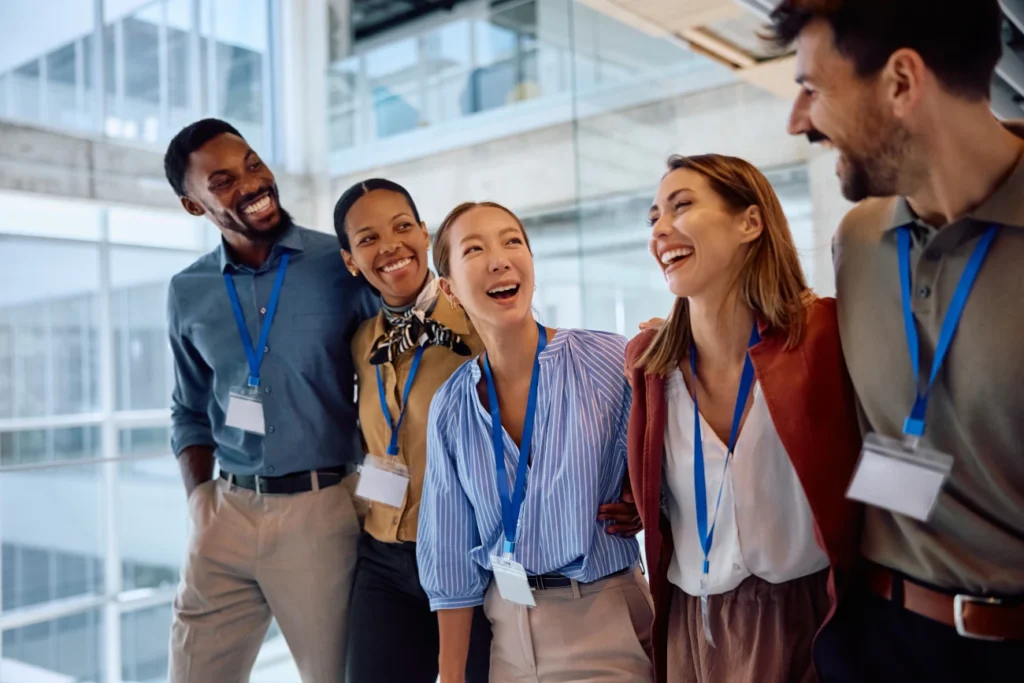 Grupo de profissionais reunidos em ambiente corporativo moderno, usando crachás e demonstrando união e colaboração.