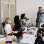 Gestor apresentando em um flip chart para a equipe em uma sala de reunião, representando desenvolvimento de liderança