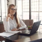 Mulher usando laptop com café — LMS fácil de usar