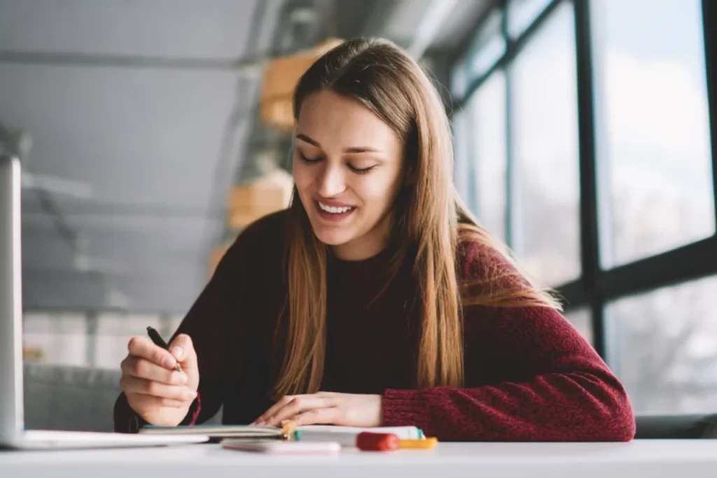 Mulher sorridente estudando em frente ao laptop, representando o uso acessível do TalentLMS para treinamento corporativo na América Latina.