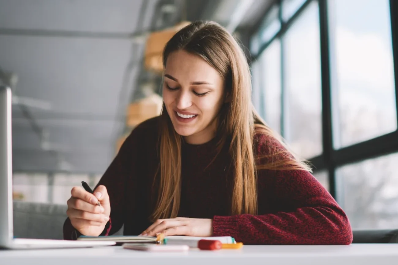 Mulher sorridente estudando em frente ao laptop, representando o uso acessível do TalentLMS para treinamento corporativo na América Latina.